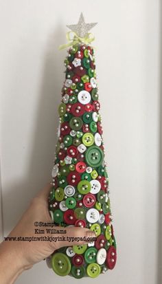 a hand holding a christmas tree made out of buttons