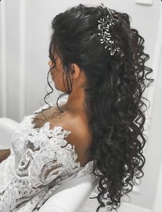 a woman with curly hair wearing a wedding dress and tiara, sitting on a white chair