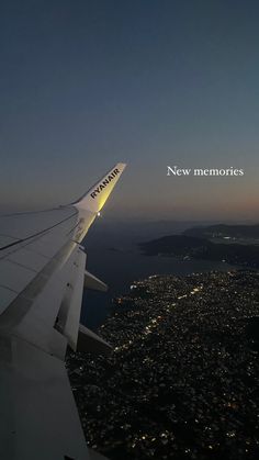 the wing of an airplane flying over a city at night with new memories written on it