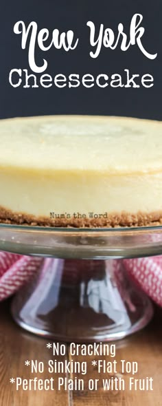 a cheesecake sitting on top of a wooden table next to a glass cake plate