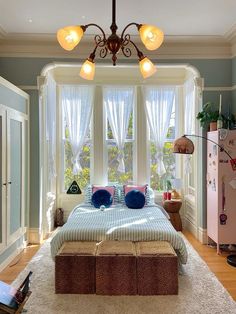 a bedroom with a bed, dresser and window in the corner is decorated in pastel colors