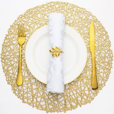 a white plate topped with a gold fork and knife next to a white napkin on top of a table