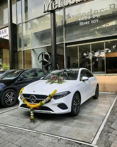 two mercedes cars parked in front of a building with flowers on the hood and wreath