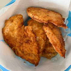 some fried food in a paper bowl on top of a blue and white table cloth