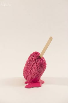 an ice cream scooper with pink icing on it and a wooden stick sticking out of the top