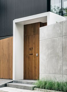 a wooden door on the side of a building with grass growing in front of it