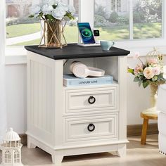 a white nightstand with drawers and a phone on top