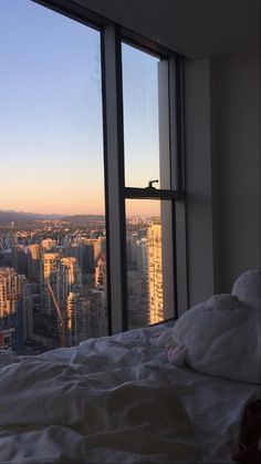 a bedroom with large windows overlooking the city