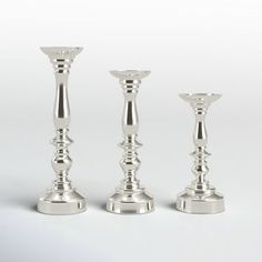 three silver candlesticks sitting next to each other