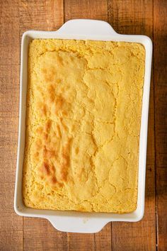 a square casserole dish filled with cornbread on top of a wooden table