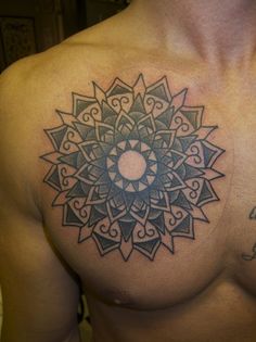 a man with a tattoo on his chest has a circular design on it's chest