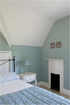 a bedroom with blue walls and a white fireplace in the corner next to a bed