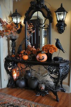 a table with pumpkins, candles and other decorations in front of a mirror on the wall