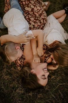 three people laying on the ground with their heads together