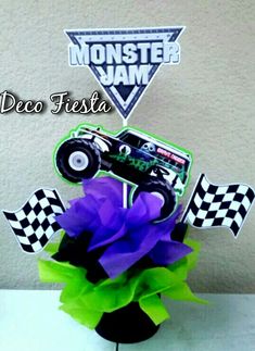 a monster truck centerpiece with purple tissue flowers in front of a sign that says deco fiesta