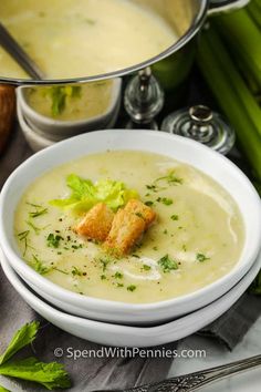 a bowl of soup with celery and bread croutons on the side