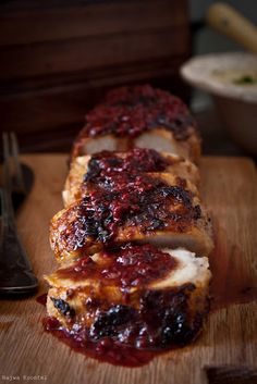 sliced meat with cranberry sauce on it sitting on a cutting board