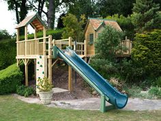 a wooden play set with a blue slide and green climbing frame in the foreground