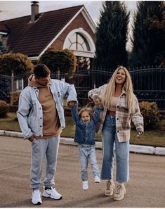 a man, woman and child walking in front of a house with their hands in the air