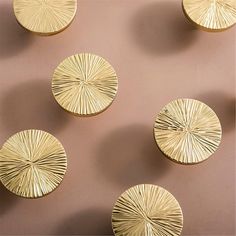 four gold plates sitting next to each other on top of a brown surface with white lines