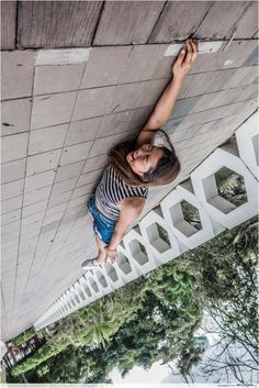 a woman climbing up the side of a white building with trees in the foreground