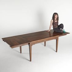 a woman sitting on top of a wooden table