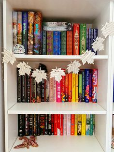 a book shelf filled with lots of books next to a pile of paper birds on top of them