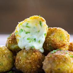 some food is sitting on a plate with green stuff in the middle and white sauce coming out of it