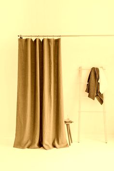 a white chair sitting in front of a window next to a curtain and towel rack