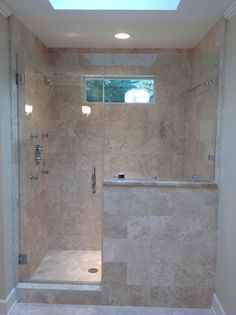 a walk in shower sitting next to a bath tub under a skylight on top of a tiled floor