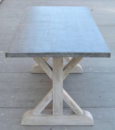 a wooden table sitting on top of a cement floor next to a sidewalk with no one around it