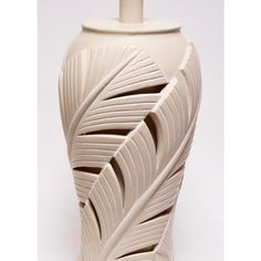 a white vase with an intricate design on the front and sides, sitting against a white background