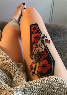 a woman's legs with a tattoo on her leg and red flowers in the shape of a letter