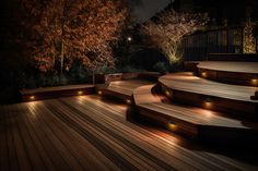 an outdoor deck lit up at night with lights on the steps and trees in the background