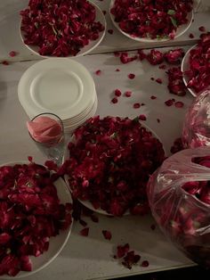 plates and bowls filled with rose petals on a table