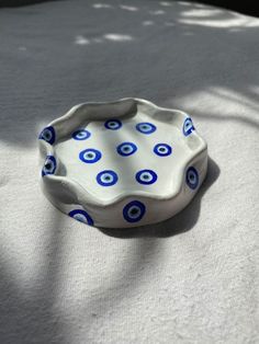 a blue and white bowl sitting on top of a bed next to a shadow cast tree