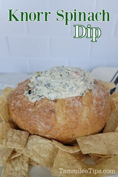 a bread bowl filled with dip surrounded by tortilla chips