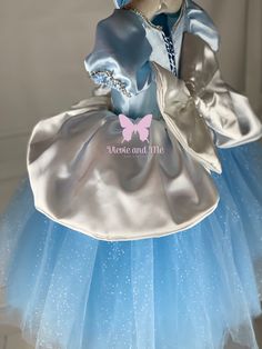 a teddy bear dressed in a blue and silver dress with a butterfly on it's head