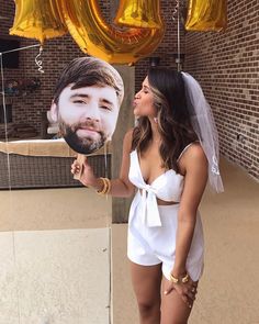 a woman holding up a balloon with the face of a man in front of her