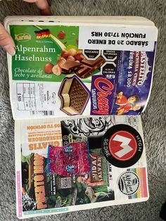 a person holding up a box filled with different types of food and candys on top of carpeted flooring