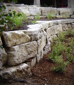 a stone wall in the middle of a garden