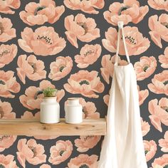 the wallpaper has pink flowers on it and is next to two white vases