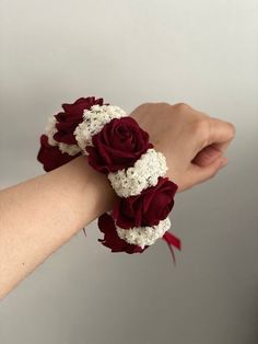 a woman's arm wearing a bracelet with red roses and white hydrangeas