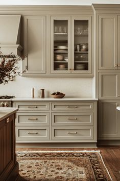 a kitchen with gray cabinets and white counter tops, an area rug on the floor