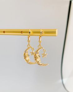 Radiate celestial elegance with The Moon Goddess Huggie Earrings. These earrings capture the allure of lunar beauty in a mesmerizing design. Meticulously crafted, the mini moon and goddess charms exude a sense of ethereal grace and power. The huggie style ensures a secure fit, promising comfort throughout the day. Whether you're drawn to cosmic mystique or seek unique accessories, these earrings make a statement. Perfect for both casual outings and special occasions, they infuse your ensemble wi Mystical Moon Shaped Earrings, Elegant Half Moon Earrings With Moon Charm, Gold Moon-shaped Earrings, Mystical Gold Earrings With Sun And Moon Design, Celestial Half Moon Single Earring, Mystical Gold Moon Phase Earrings, Gold Moon Phase Earrings, Mystical Crescent Earrings For Gift, Gold Moon-shaped Earrings With Moon Charm