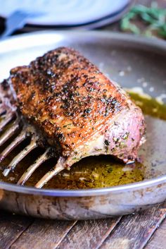 a piece of meat on a fork in a pan with oil and pepper sprinkled over it