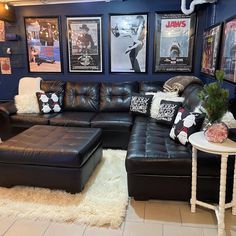 a living room with black leather furniture and pictures on the wall above it's couch