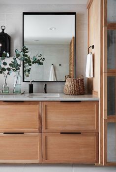 a bathroom with wooden cabinets and a large mirror on the wall over the sink area