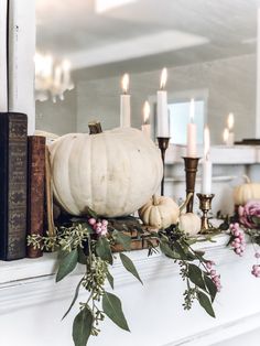 a white pumpkin sitting on top of a mantle next to some books and other decorations