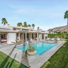 a house with a swimming pool in front of it and palm trees around the pool